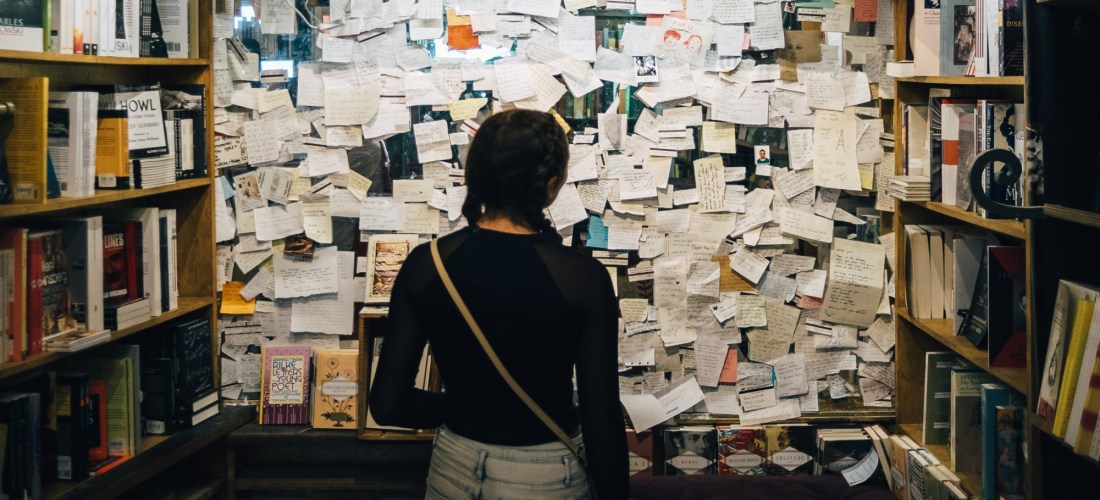 A person stands in front of a bulletin board filled with cards and handwritten notes